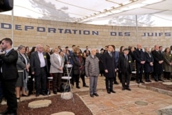 Holocaust survivor Saul Oren, center left, French President Emmanuel Macron, center, and historian and former Nazi hunter Serge Klarsfeld observe a moment of silence at the Roglit memorial in Neve Michael, west of Jerusalem, Jan. 23, 2020.