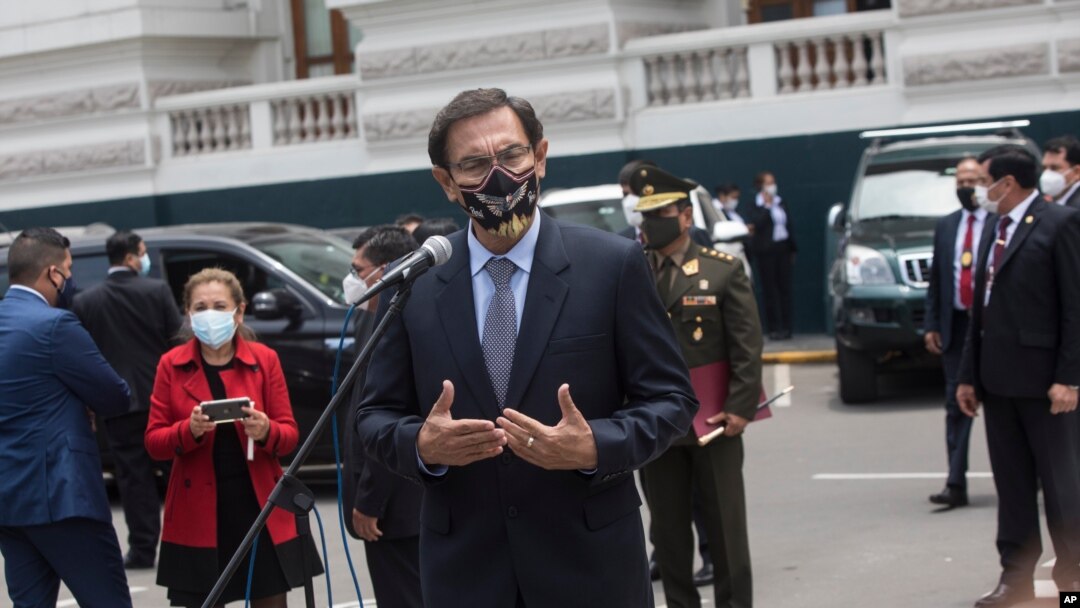 Con una máscara en medio de la pandemia de COVID-19, el presidente peruano, Martín Vizcarra, habla con los reporteros después de salir del Congreso en Lima, Perú, el lunes 9 de noviembre de 2020.