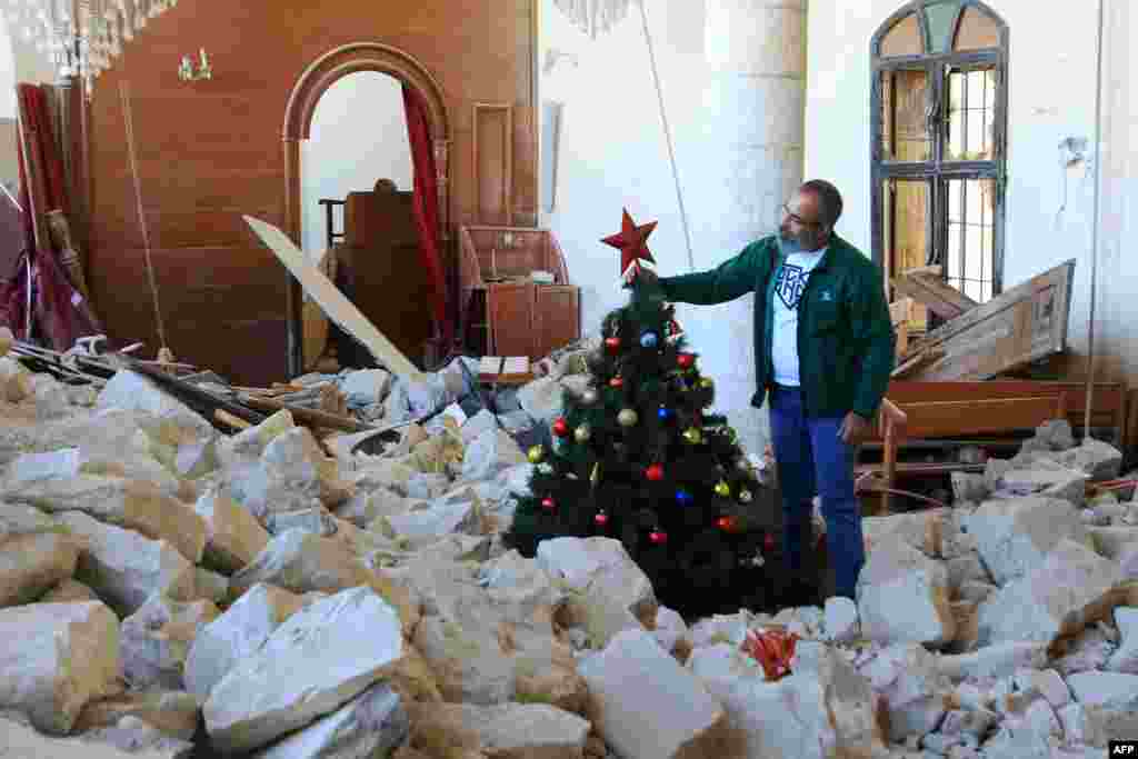 A man sets up a Christmas tree amidst the rubble of the Melkite Church, which was hit by an Israeli airstrike on Oct. 9, in the southern Lebanese village of Derdghaya.