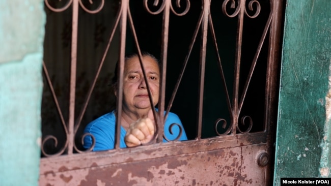 Jaqueline Cuquejo, de 62 años, asomada por la puerta de su casa, ubicada en una barriada pobre de Caracas