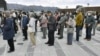 People wearing protective face masks form a line while keeping distance from others as they try to watch the Olympic flame during the Tokyo 2020 Olympics Flame of Recovery tour in Ofunato, March 23, 2020. (Kyodo/via Reuters)