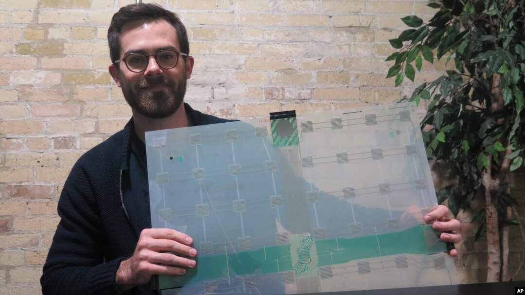 FILE - Scanalytics co-founder and CEO Joe Scanlin holds a smart-floor sensor his company creates that tracks people's movements, in Milwaukee, Wisconsin, Dec. 5, 2017. 