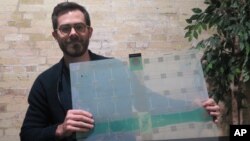 FILE - Scanalytics co-founder and CEO Joe Scanlin holds a smart-floor sensor his company creates that tracks people's movements, in Milwaukee, Wisconsin, Dec. 5, 2017. 