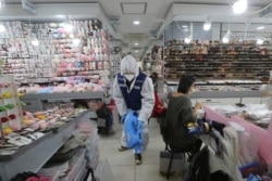 Seorang pekerja yang mengenakan baju pelindung menyemprotkan desinfektan di dalam sebuah toko sebagai tindakan pencegahan terhadap virus corona baru di Pasar Namdaemun di Seoul, Korea Selatan. (Foto: AP)
