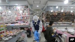 A worker wearing protective gears sprays disinfectant inside a store as a precaution against a new coronavirus at Namdaemun Market in Seoul, South Korea, Wednesday, Feb. 5, 2020. 