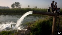 En India, dos personas conversan mientras extraen agua de un pozo para su cosecha en el Día Mundial del Agua, en las afueras de Nueva Delhi, India, el miércoles, 22 de marzo, de 2017. 