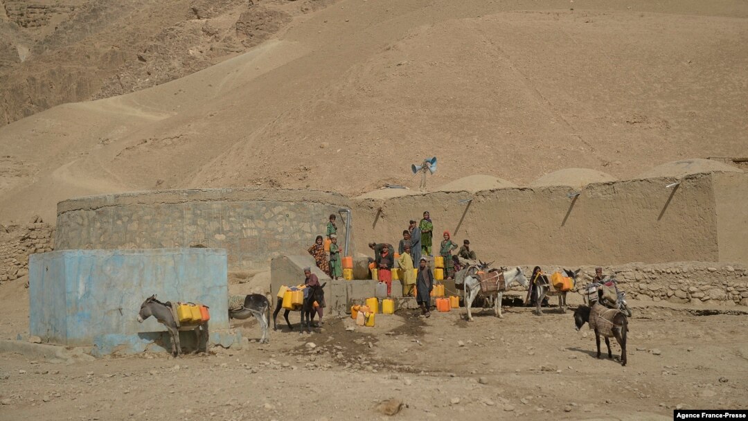 This picture taken on October 15, 2021 shows children filling jerrycans with water from a water storage in Bala Murghab district of Badghis province.