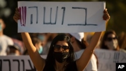 An Israeli social worker holds a sign in Hebrew that reads, "shame," during a protest against the economic situation in the central Israeli town of Kfar Ahim, July 9, 2020.