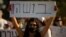 An Israeli social worker holds a sign in Hebrew that reads, "shame," during a protest against the economic situation in the central Israeli town of Kfar Ahim, July 9, 2020.