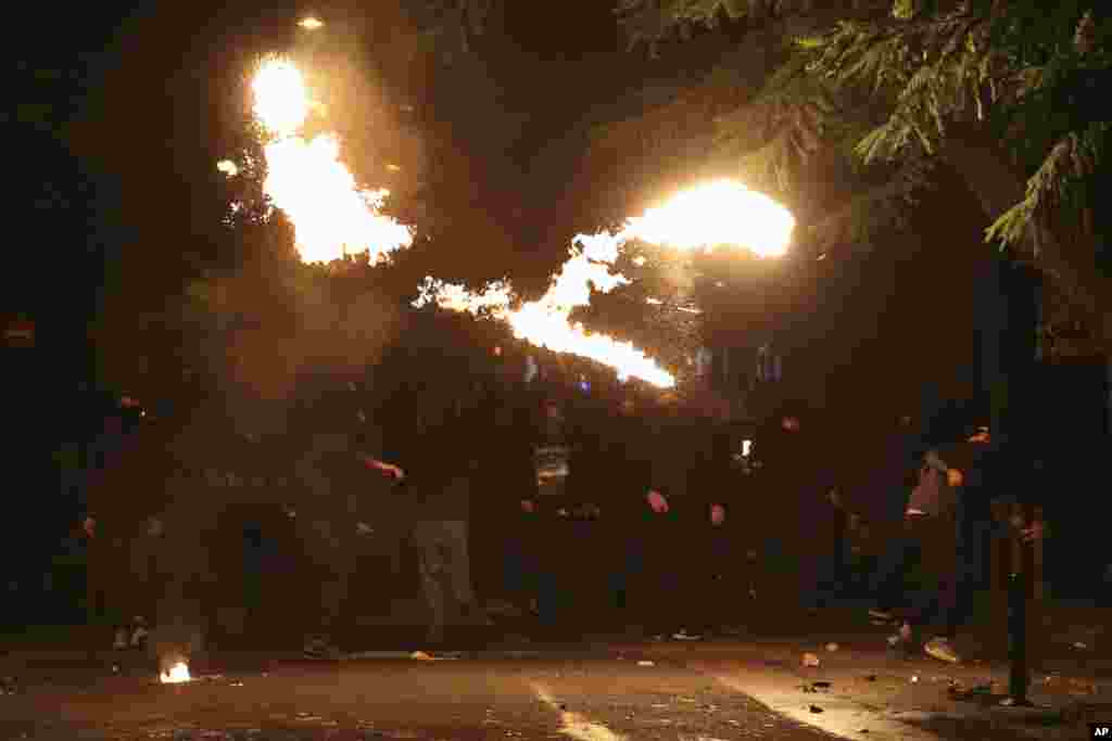 Hooded youths throw petrol bombs at riot police during clashes in Athens, Greece. Riots broke out in central Athens after dozens of youths march peacefully to commemorate the police killing of a teenager eight years ago.