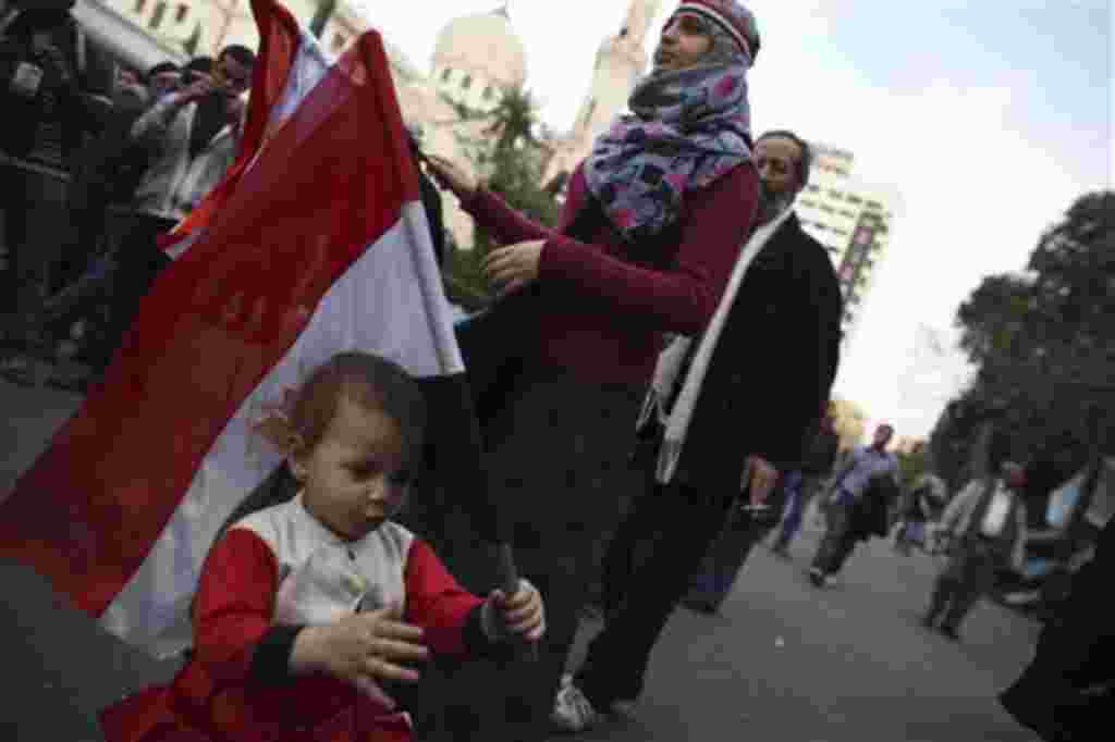 An anti-government protester stands with her daughter as they carry Egyptian flags outside the Egyptian Parliament in Cairo, Egypt, Wednesday, Feb. 9, 2011. Around 2,000 protesters waved huge flags outside the parliament, several blocks from Tahrir Square