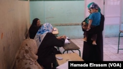 Une femme avec un enfant dans un bureau de vote à Giza, Egypte, 18 octobre 2015.