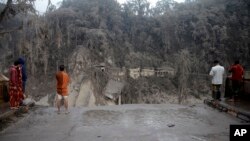 Villagers look at the broken bridge destroyed by the lava flow by the eruption of Mount Semeru in Lumajang district, East Java province, Indonesia, Dec. 5, 2021.