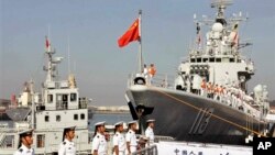 In this Tuesday, Aug. 20, 2013 photo, Chinese navy sailors stand on the guided-missile destroyer, Qingdao, right, before departure for a naval drill at a military port in Qingdao in east China's Shandong province. Three Chinese ships are sailing east to 