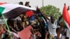 FILE - People shout slogans as tens of thousands of people march on the streets demanding the ruling military hand over to civilians, in Khartoum, Sudan, June 30, 2019.