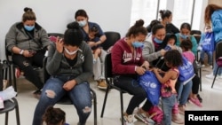 FILE - Asylum-seeking migrants from Central America, who were airlifted from Brownsville to El Paso, Texas, and deported from the U.S., wait inside the office of the Center for Integral Attention to Migrants in Ciudad Juarez, Mexico, March 16, 2021.