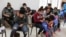 FILE - Asylum-seeking migrants from Central America, who were airlifted from Brownsville to El Paso, Texas, and deported from the U.S., wait inside the office of the Center for Integral Attention to Migrants in Ciudad Juarez, Mexico, March 16, 2021.