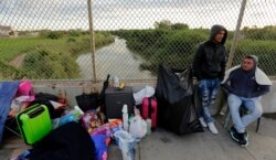 FILE - Yenly Morales, left, and Yenly Herrera, right, immigrants from Cuba seeking asylum in the United States, wait on the Brownsville and Matamoros International Bridge in Matamoros, Mexico, Nov. 2, 2018.