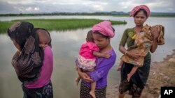 Rohingya Muslim women, who crossed over from Myanmar into Bangladesh, stand holding their sick children after Bangladesh border guard soldiers refused to let them journey towards a hospital and turned them back towards the zero line border in Palong Khali, Bangladesh, Wednesday, Oct. 18, 2017. 