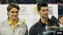 Novak Djokovic (kanan) dan Roger Federer (kiri) memegang trofi mereka setelah partai final Kejuaraan ATP Dubai bulan lalu. Keduanya akan ikut pertandingan sepak bola amal bagi upaya pemulihan bencana Jepang.