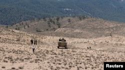 FILE - Tunisian soldiers patrol near the border with Algeria as seen from the area of Mount Chambi, west Tunisia, June 11, 2013.