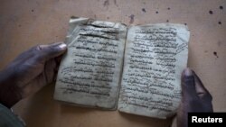 Aboubakar Yaro, head of conservation at the Djenne Library of Manuscipts, holds an Islamic manuscript from the 15th century, September 1, 2012.