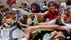 Yemeníes muestran sus tarjetas de identificación para poder recibir alimentos de una organización caritativa en Sanaa, Yemen, en abril de 2017.