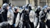 Police officers in riot gear gesture with batons during a demonstration held in reaction to the fatal stabbings in Southport on July 29, outside the Liver Building in Liverpool, England, on Aug. 3, 2024.