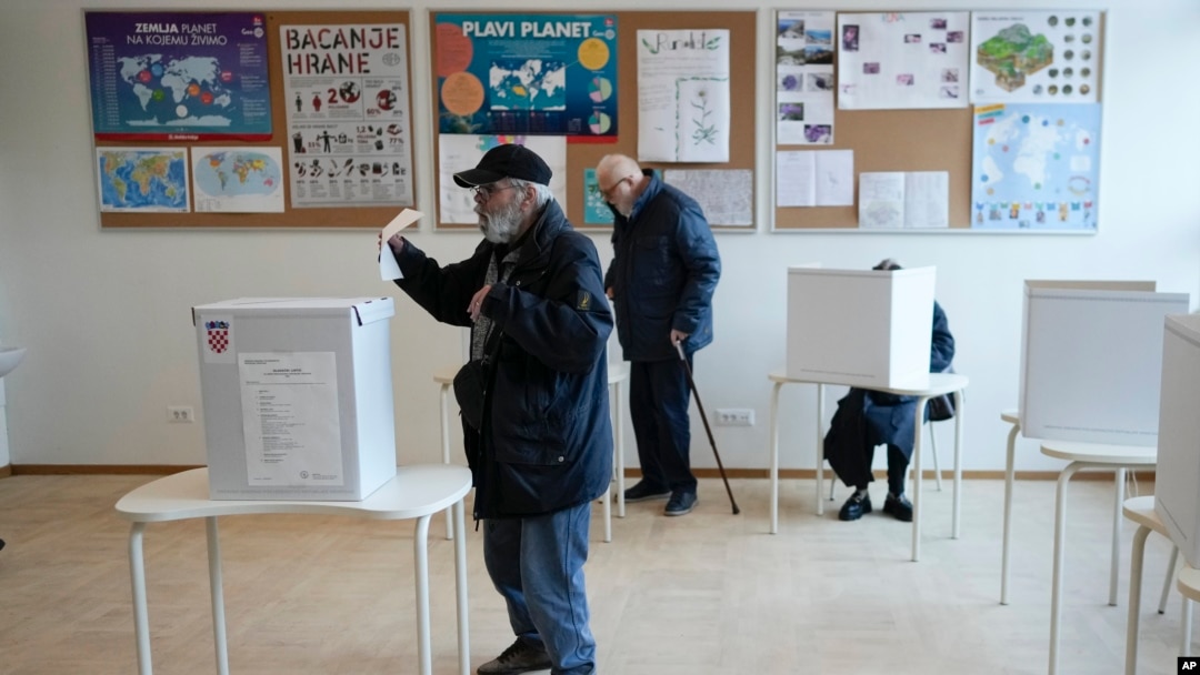 Seorang pria memasukkan surat suara dalam pilpres Kroasia di sebuah TPS di Zagreb, Kroasia, Minggu, 29 Desember 2024. (Foto: Darko Bandic/AP Photo)