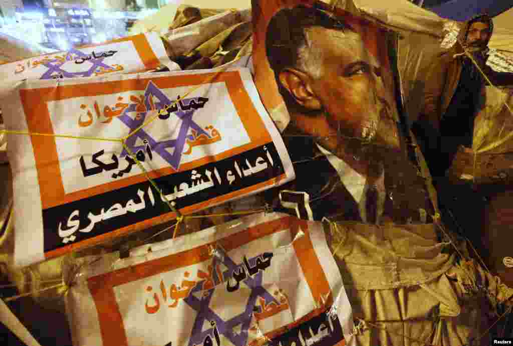 A protester opposing Egyptian President Mohamed Mursi walks outside tents near a picture Egypt's former President Gamal Abdel Nasser during a sit-in at Tahrir Square in Cairo, January 31, 2013. 