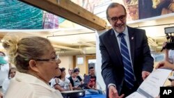 FILE - Carlos Sada, Mexico's consul in Los Angeles presents Irma Rodriguez Guevara, from El Salvador (L), with her computer studies certificate in Los Angeles, Sept. 3, 2015.