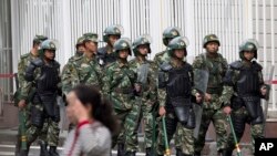 FILE - Paramilitary policemen with shields and batons patrol near the People's Square in Urumqi, China's northwestern region of Xinjiang.