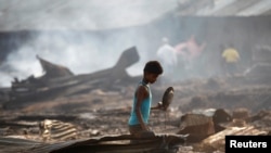 Seorang anak laki2 mencari barang-barang yang dianggap masih berguna di antara benda-benda yang hangus terbakar setelah kebakaran memporak porandakan kamp penampungan pengungsi Rohingya di dekat Siitwe, Myanmar (3/5). 