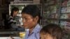 This Aug. 26, 2009 photo shows a merchant in Pailin, Cambodia speaking with a woman as she holds her sick child at a drug store. Posters with message: “Counterfeit medicine kills, while real medicine heals” will be distributed to public hospitals, health 