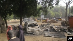 Children stand near the scene of an explosion in a mobile phone market in Potiskum, Nigeria, Jan. 12, 2015. Two female suicide bombers targeted the busy marketplace on Sunday.