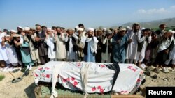 FILE - Relatives and residents pray near a coffin during a funeral ceremony of one of the victims after a drone strike, in Khogyani district of Nangarhar province, Afghanistan Sept. 19, 2019.