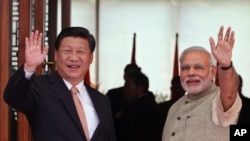 PM India Narendra Modi (kanan) dan Presiden China Xi JInping melambaikan tangan kepada media, setibanya di sebuah hotel di Ahmadabad, India, Rabu (17/9). 