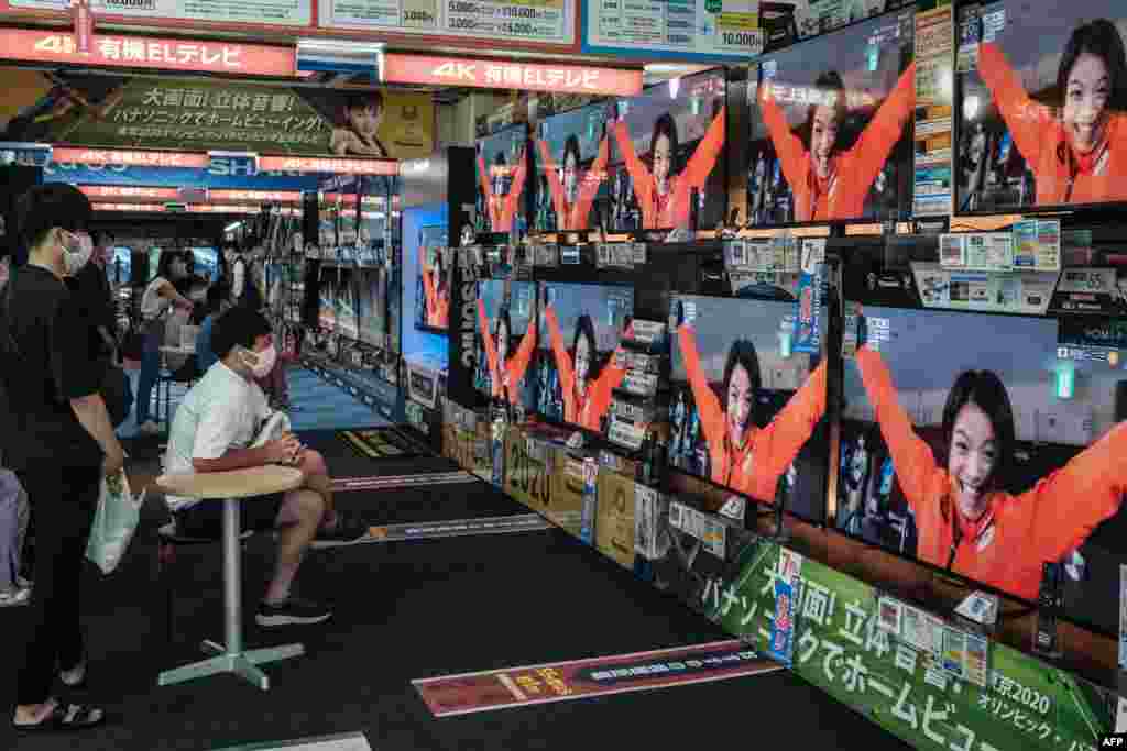 TVs in a Tokyo electronics shop display the reaction of Japan's Uta Abe, a gold medallist in judo, as her brother, Hifumi Abe, wins the men's 66kg judo final in Tokyo on July 25, 2021.