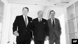 In this Jan. 9, 1985 file photo, Secretary of State George Shultz, center, walks with President Ronald Reagan and Vice President George Bush upon his arrival at the White House in Washington. 