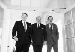 Nesta foto de Janeiro de 1985, Secretário de Estado George Shultz, no centro; Presidente Ronald Reagan, esquerda; Vice-Presidente George Bush, direita, na Casa Branca