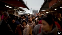 FILE - In this Saturday, March 4, 2017 file photo, people walk along street stalls at a fruit market in The Hague, The Netherlands. In The Hague's most culturally diverse neighbourhoods, many women wear Muslim headscarves. The Netherlands has approved a limited ban on "face-covering clothing" including Islamic veils and robes such as the burqa and niqab in several public places after a vote of the parliamentary first chamber on Tuesday June 26, 2018.