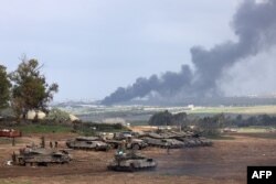 Tentara Israel berdiri di samping tank di Israel dekat perbatasan dengan Jalur Gaza saat asap mengepul di Jalur Gaza setelah pengeboman Israel pada 14 Januari 2024. (Foto: AFP)