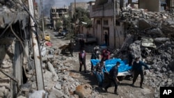 FILE - Residents carry bodies of several people killed in airstrikes during anti-Islamic state operations, in western Mosul, Iraq, March 24, 2017.