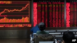 Investors monitor stock prices at a brokerage in Beijing, Jan. 16, 2020. Share prices are mixed in moderate trading in Asia after the U.S. and China signed a preliminary trade agreement.