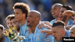 Vincent Kompany dari Manchester City mengangkat trofi saat merayakan keberhasilan Manchester City menjuarai Liga Premier Inggris di Stadion The American Express Community di Brighton, Inggris 12 Mei 2019.
