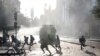 People and demonstrators run as a riot police vehicle uses a water cannon during a protest against Chile's government in Santiago, Chile, Oct. 29, 2019.