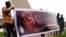 FILE - People carry a banner during a remembrance ceremony for the children who were killed during an attack on the Dogon village of Sobane Da, at the Monument de la Paix in Bamako, Mali, June 15, 2019.