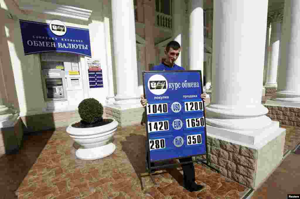 A man carries a placard with currency rates at a currency exchange office in Sevastopol, Ukraine, March 24, 2014.