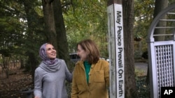 Heba Macksoud, left, of Princeton, New Jersey, and Sheryl Olitzky, members of the Sisterhood of Salaam Shalom, stand near a Peace Pole, with English and Arabic writings, in North Brunswick, New Jersey, Oct. 17, 2019.