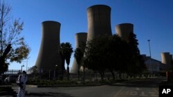 FILE - A worker blows leaves at the main entrance of the Komati Power Station in Middelburg, South Africa, June 19, 2023.